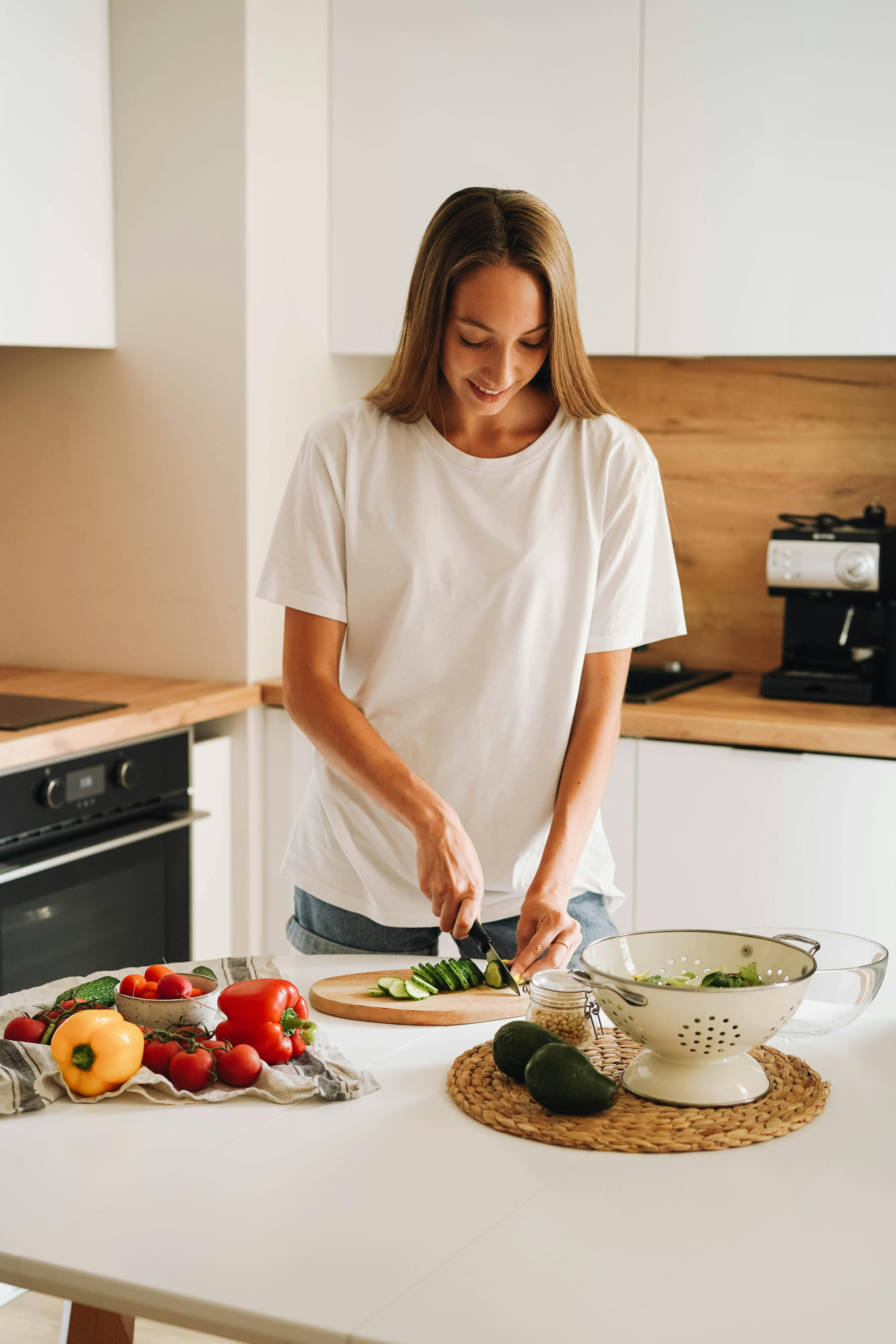 Woman chopping fresh vegetables in her kitchen, an example of the healthy eating habits that the EAP's Tier 2 supports with nutritional counselling